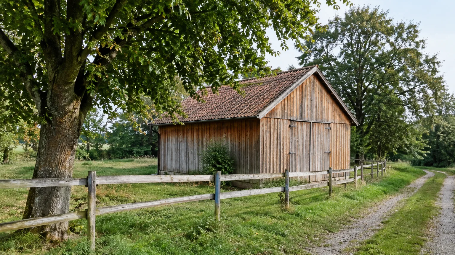 Ein unbeschädigtes hölzernes Wirtschaftsgebäude steht hinter einem einfachen Zaun.