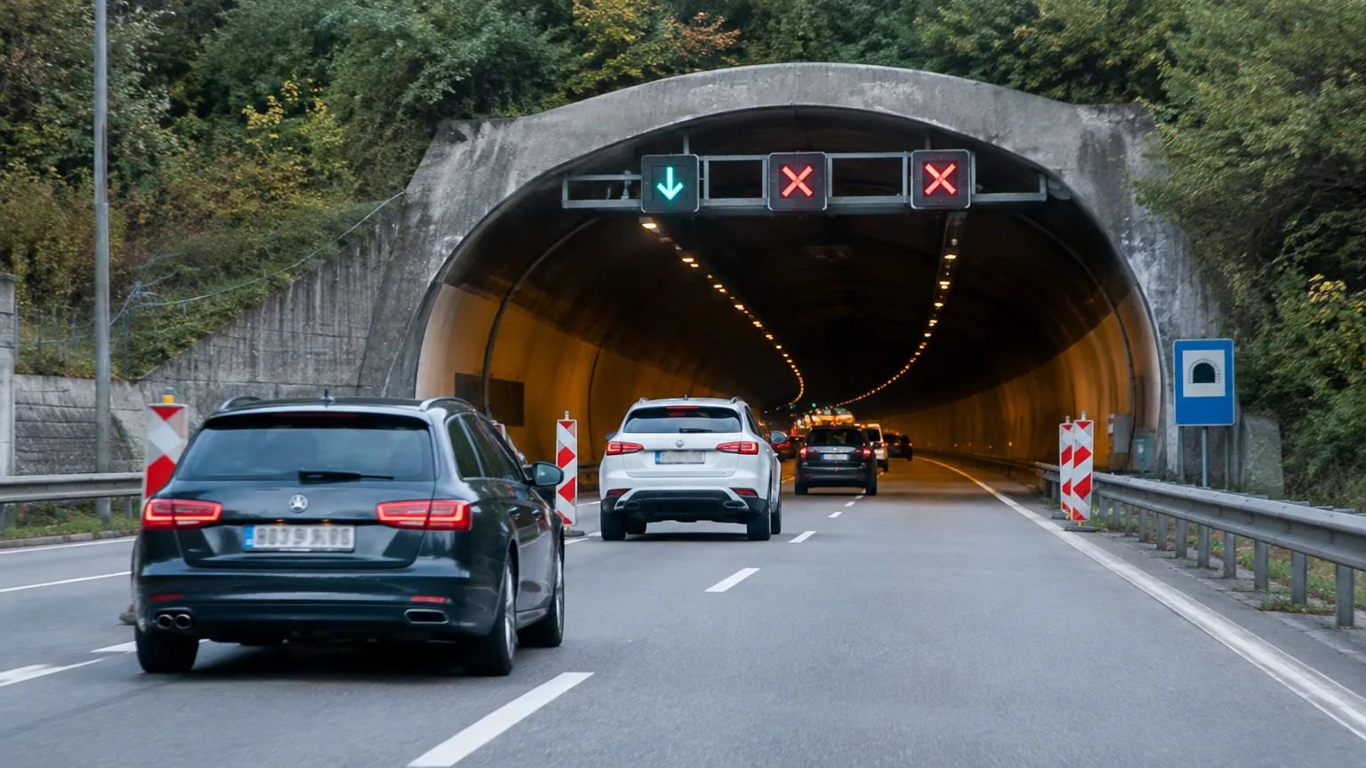 Fahrzeuge nähern sich einem Tunnel mit rot und grün leuchtenden Fahrstreifensignalen.
